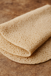 Close-up of injera showing its spongy texture and teff grain character.