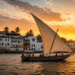 Traditional dhow sailing past the historic waterfront of Lamu Island at sunset.